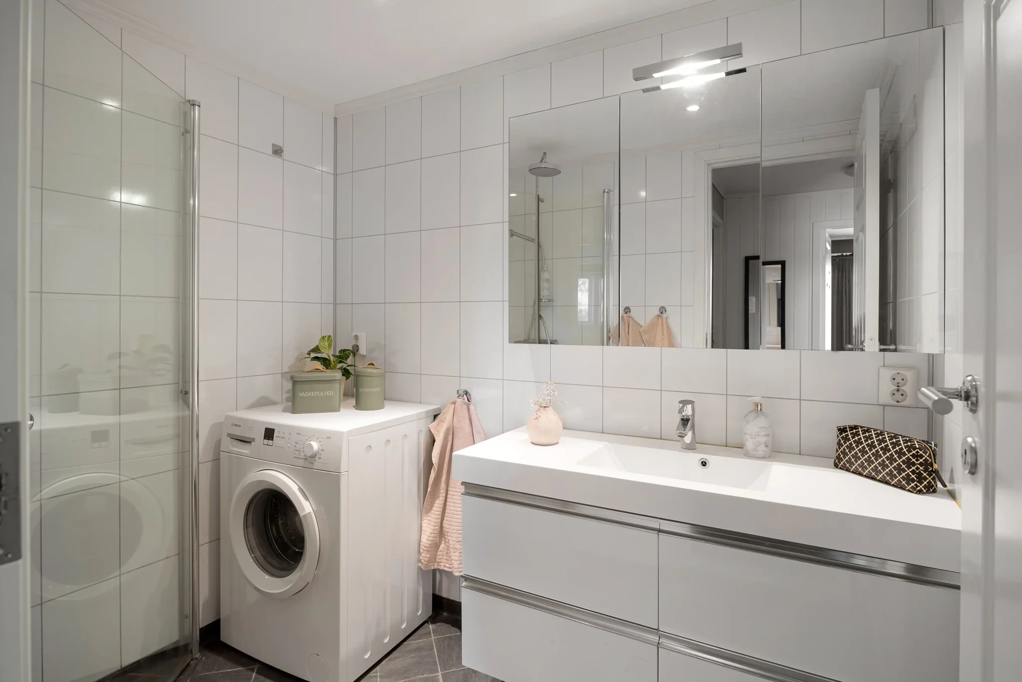 All-white square tile bathroom with integrated washing machine and shower
