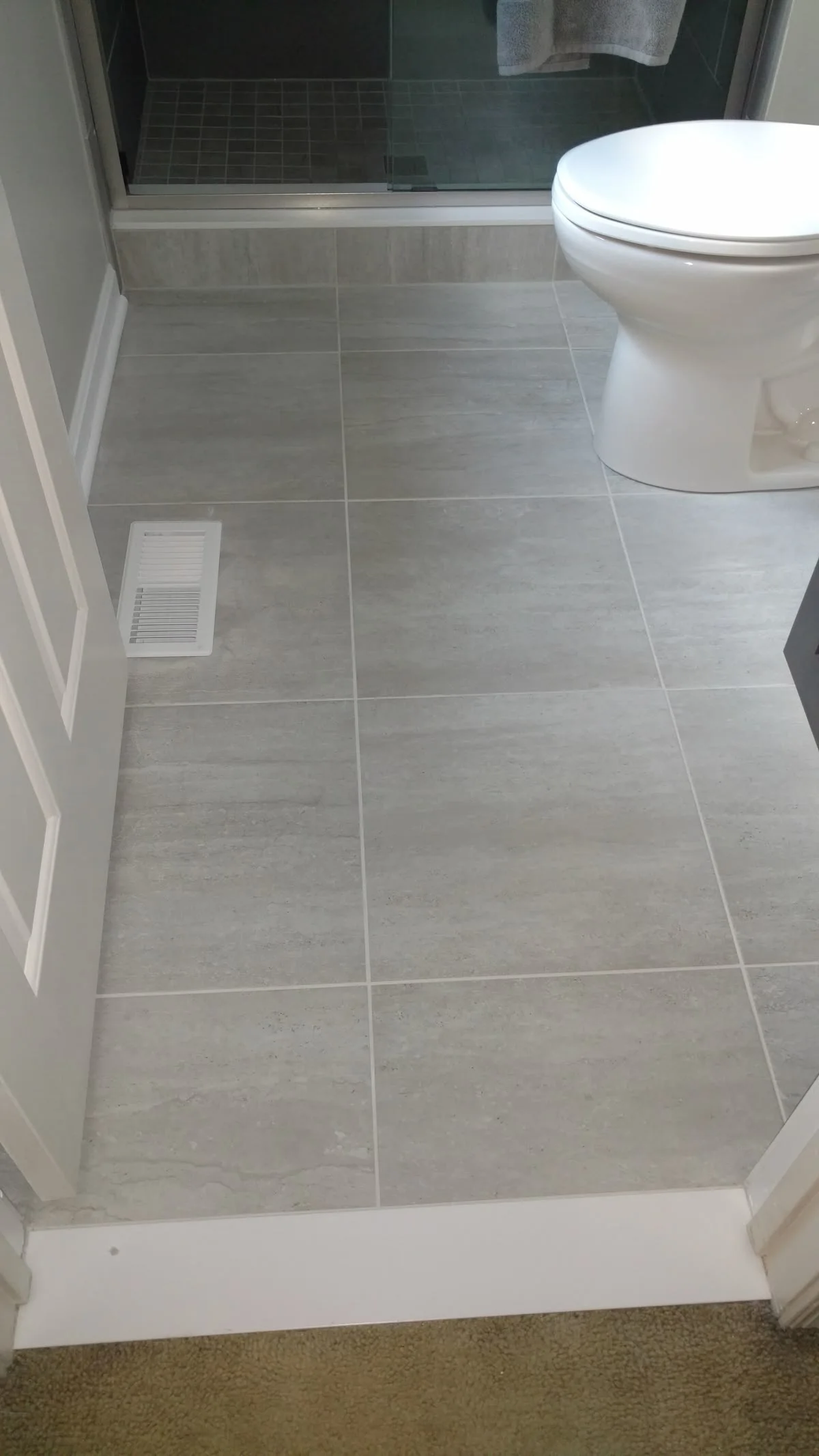 Light gray large-format floor tile in a bathroom with walk-in shower