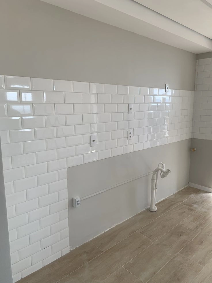 Fresh install of white beveled subway tile on the upper half of a prepped wall