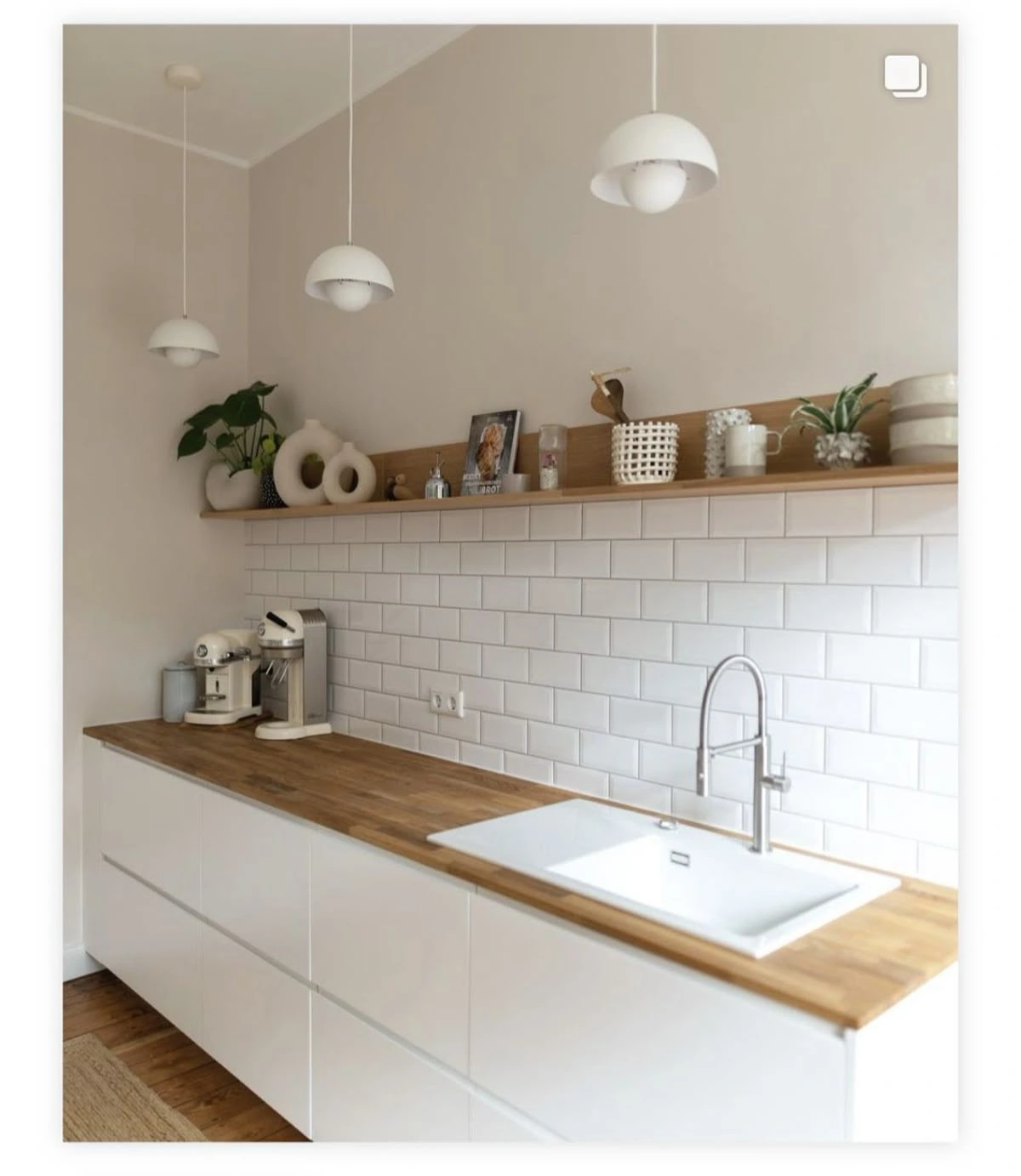 Minimalist white kitchen with wood butcher-block countertop and white subway tile backsplash