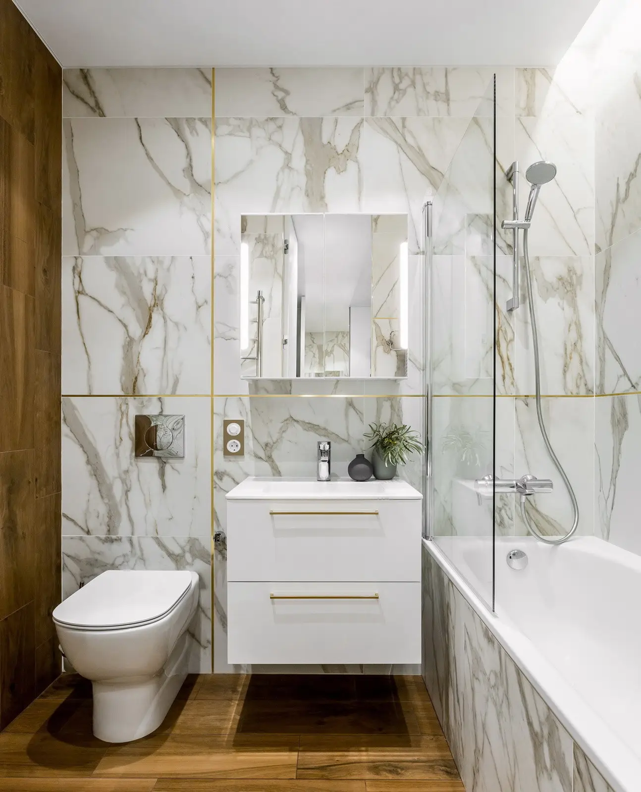 Calacatta marble-look walls with brass inlay grout lines and wood accent