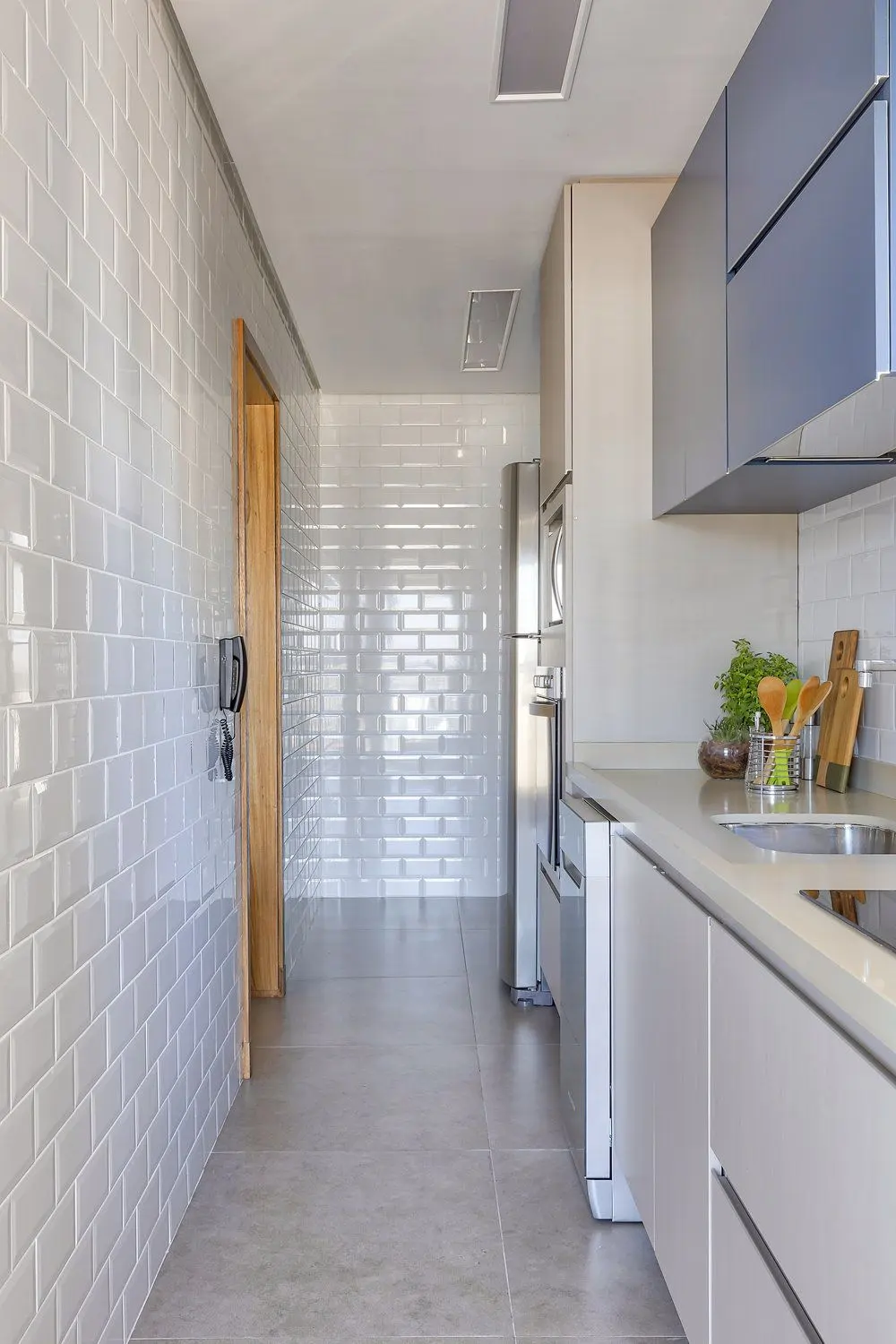Full-wall white beveled subway tile in a galley kitchen corridor